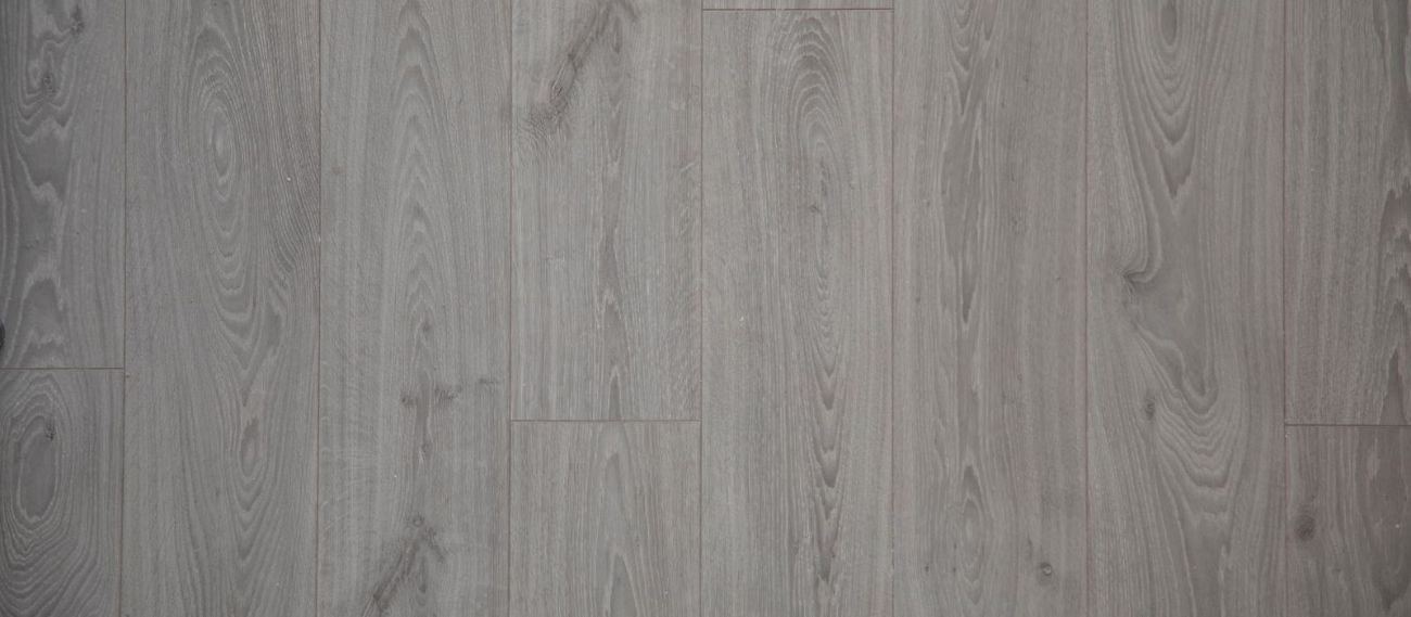 Piso laminado gris tipo WPC instalado en una sala, mostrando la veta de madera realista del material