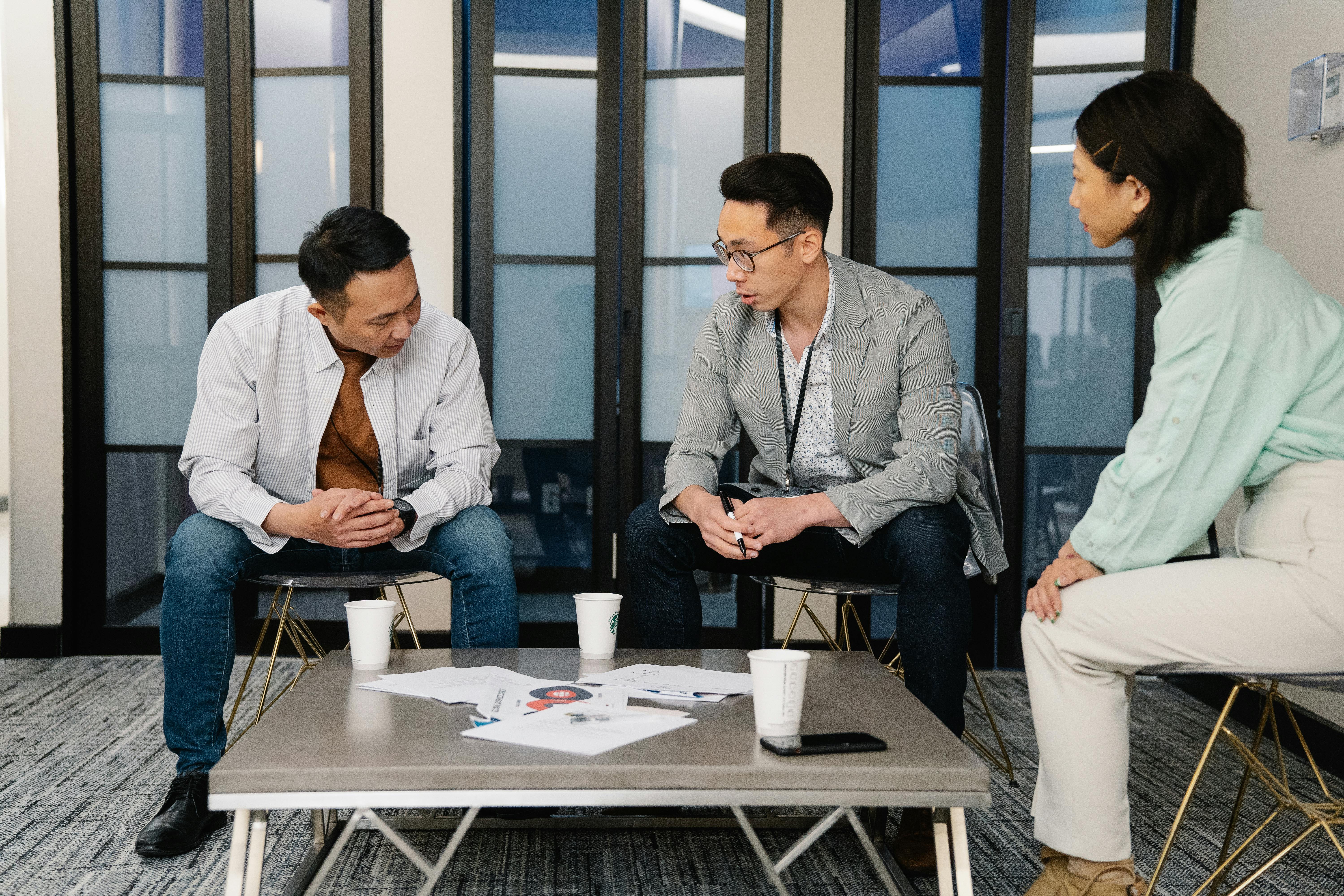 Lender and two men talking about cancelling mortgage while sitting on chairs