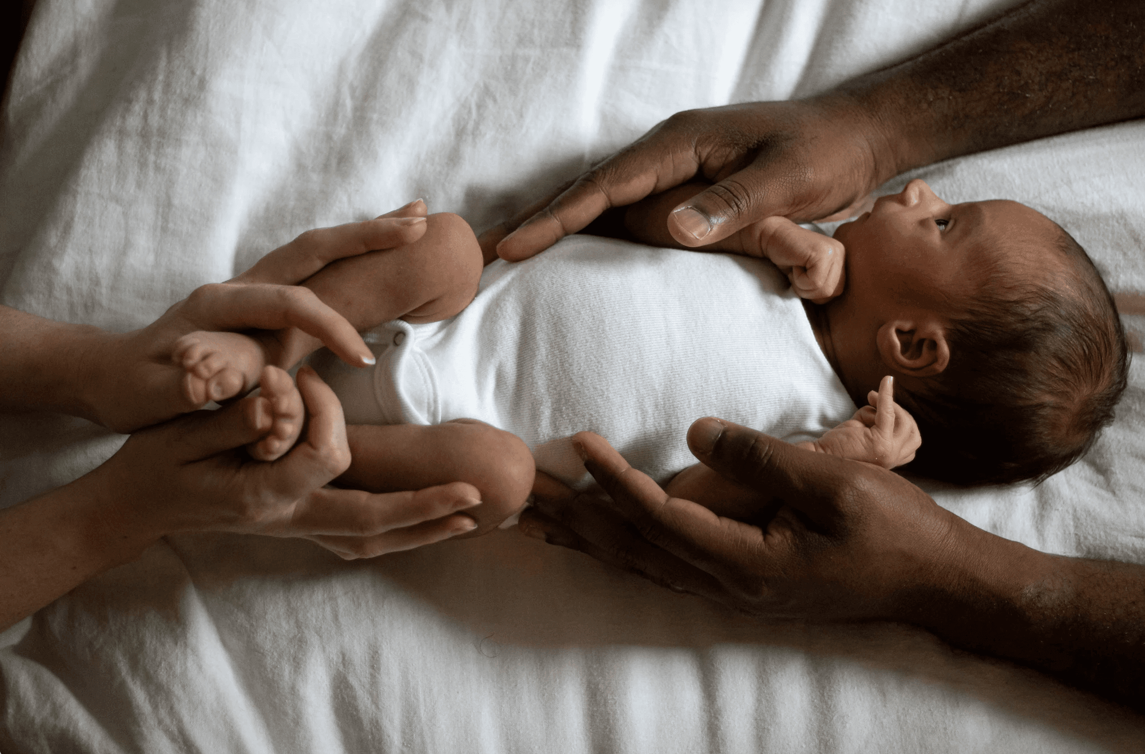 hands of man and woman envelope new baby