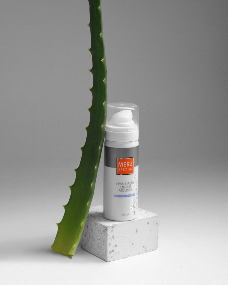 Skincare spray bottle arranged with an aloe leaf on a studio set