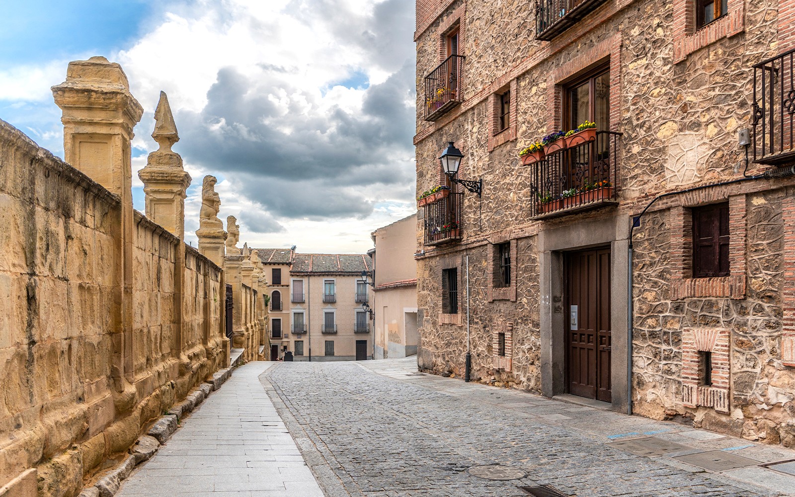 Kasseienstraat in de Joodse Wijk van Segovia, met historische stenen gebouwen en sierlijke balkons.