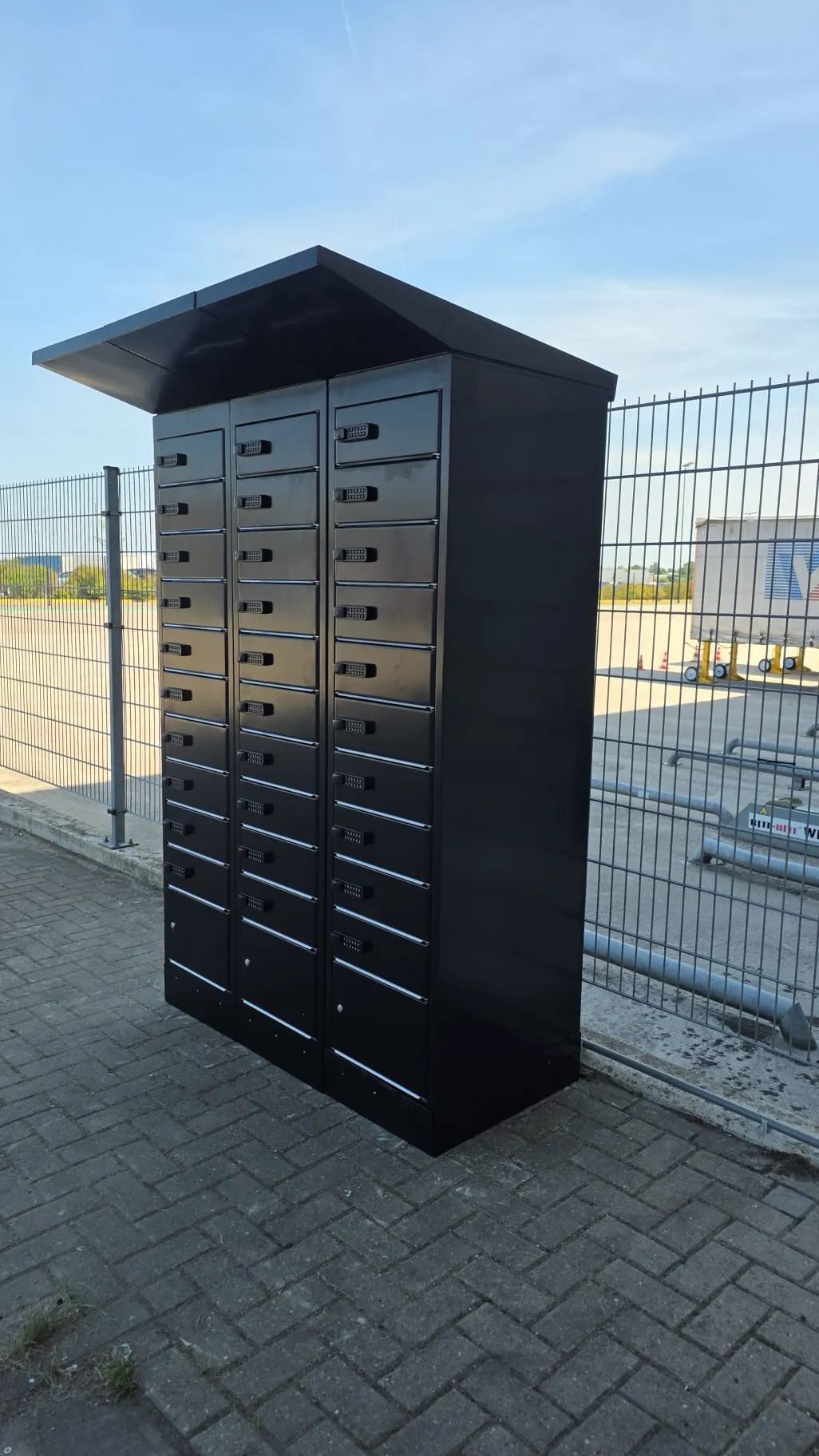 PowerShelter CoreShelter e-bike battery charging lockers installed outdoors at a warehouse site, showing three units against a security fence.