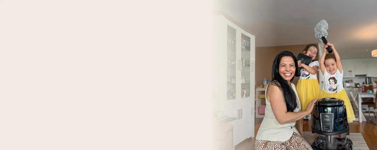 Lächelnde Mutter mit ihren beiden Kindern und dem HYLA Reinigungssystem in einem hellen Wohnzimmer