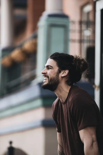 The bearded man, laughing loudly, turns his body sideways.