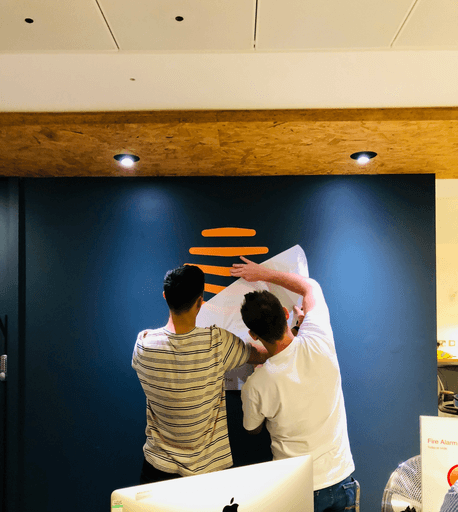 Photo of the Hive team putting up a logo on the wall