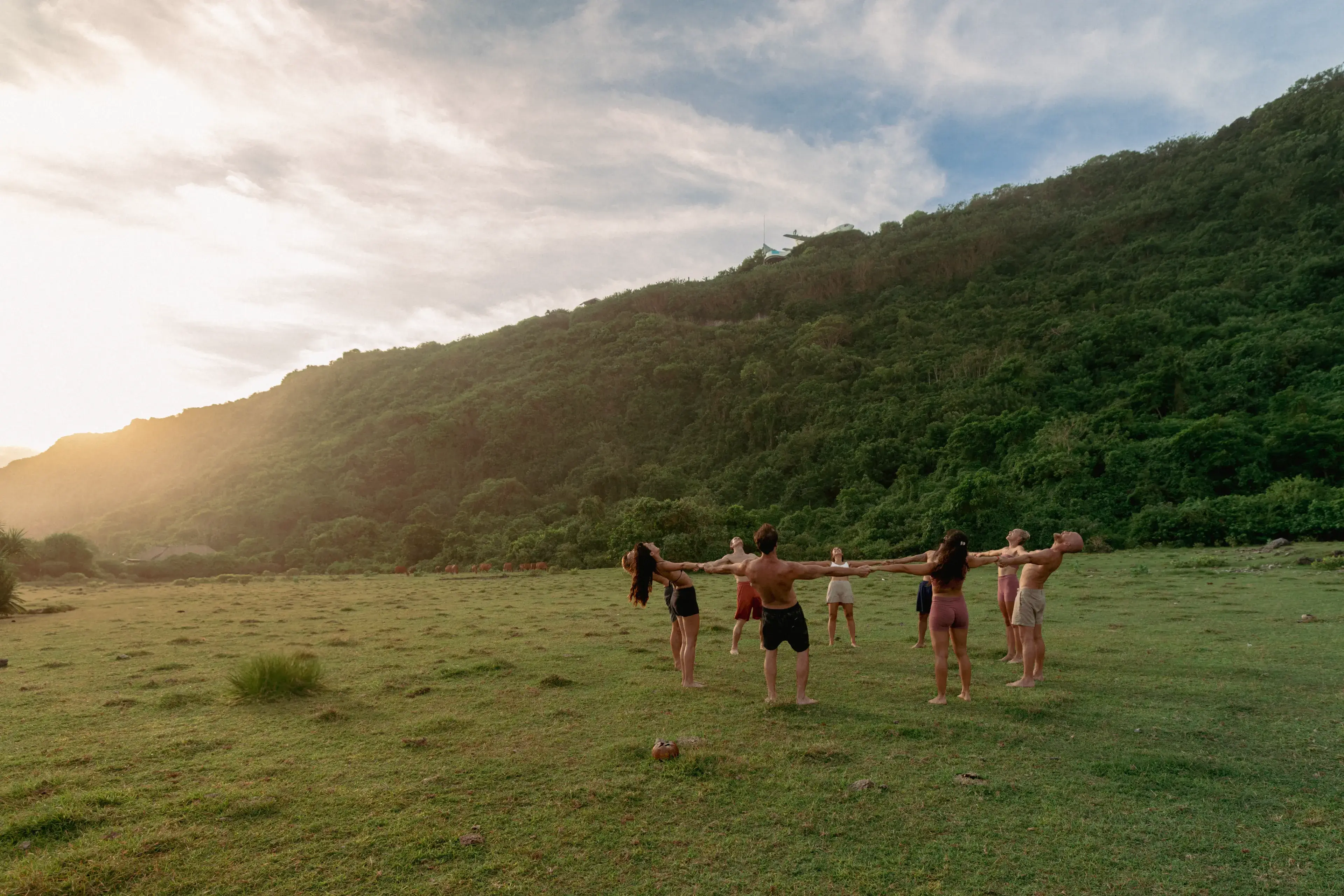 Yoga students holding hands in a community circle during a sunset nature excursion in Bali