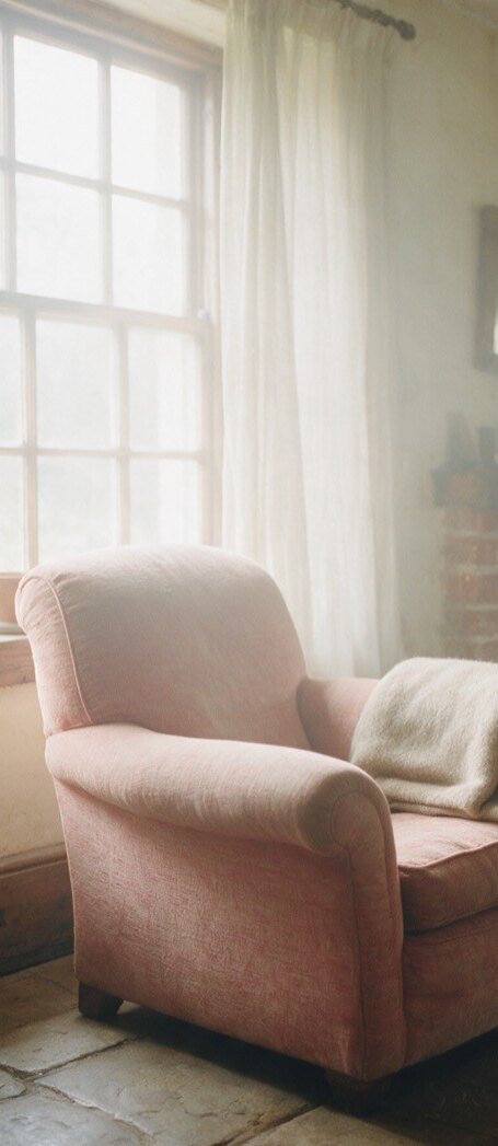 An empty armchair beside a window in a quiet sitting room
