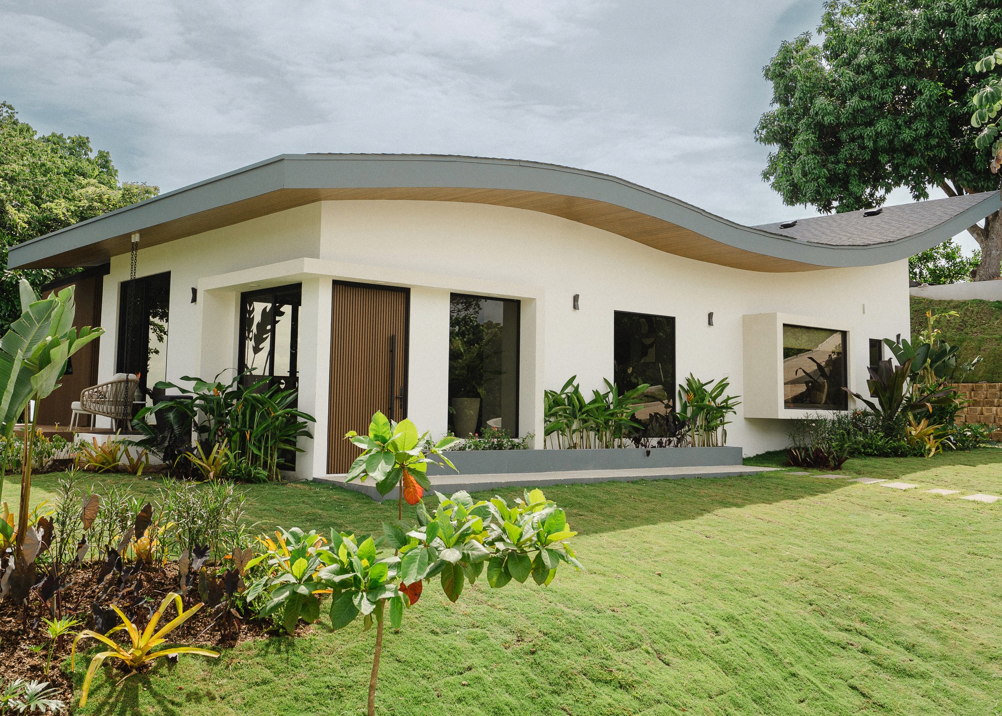 Exterior of a luxury Costa Rica vacation rental featuring unique modern architecture with a wavy roof and lush tropical gardens.