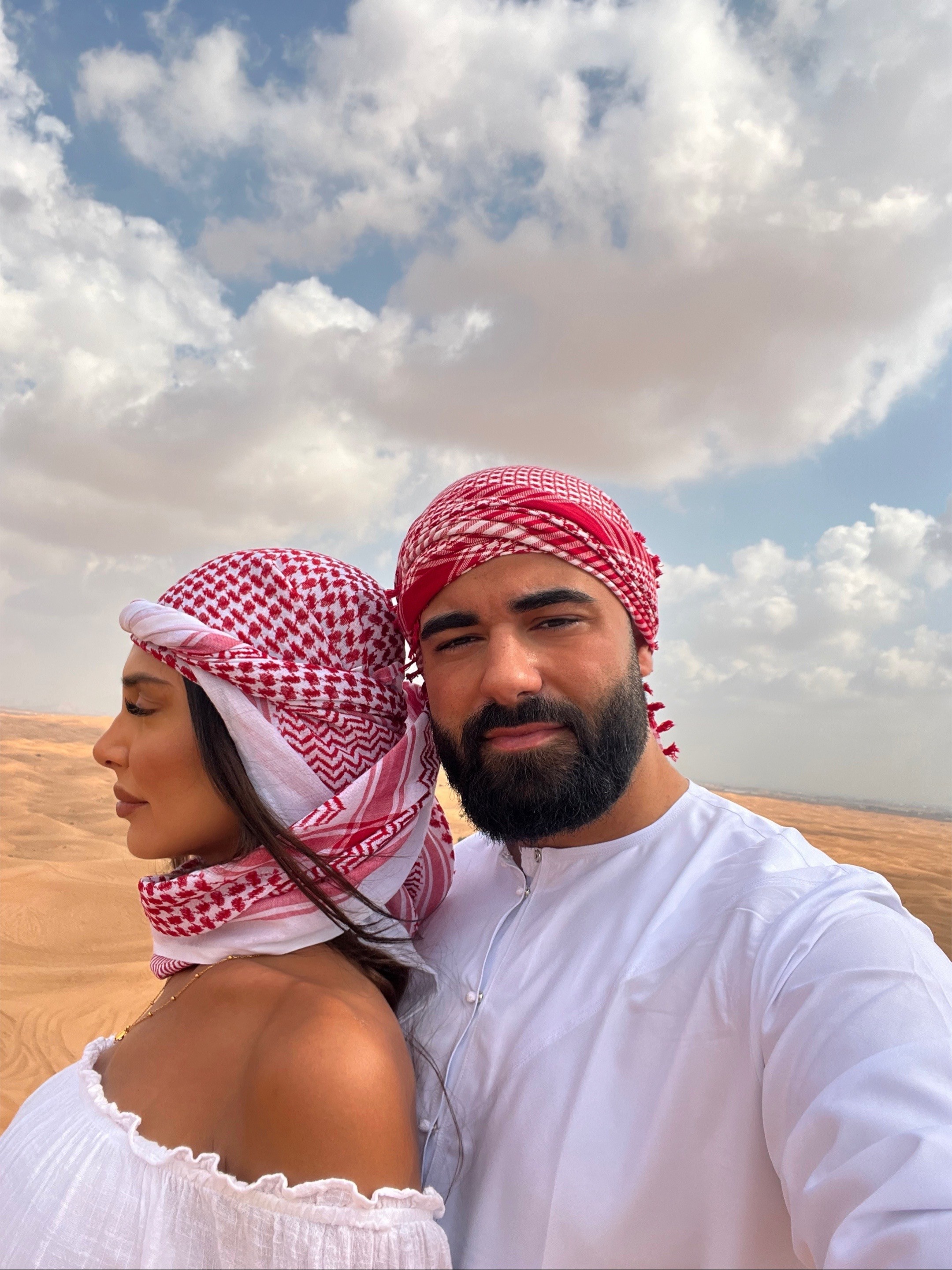 Ali Merdif and partner sharing a romantic moment in traditional keffiyehs on a Dune Quest Tours Desert Safari 2026, highlighted as a top-rated couple's activity