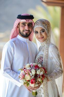 Beautiful Muslim couple in traditional wedding attire holding a bouquet