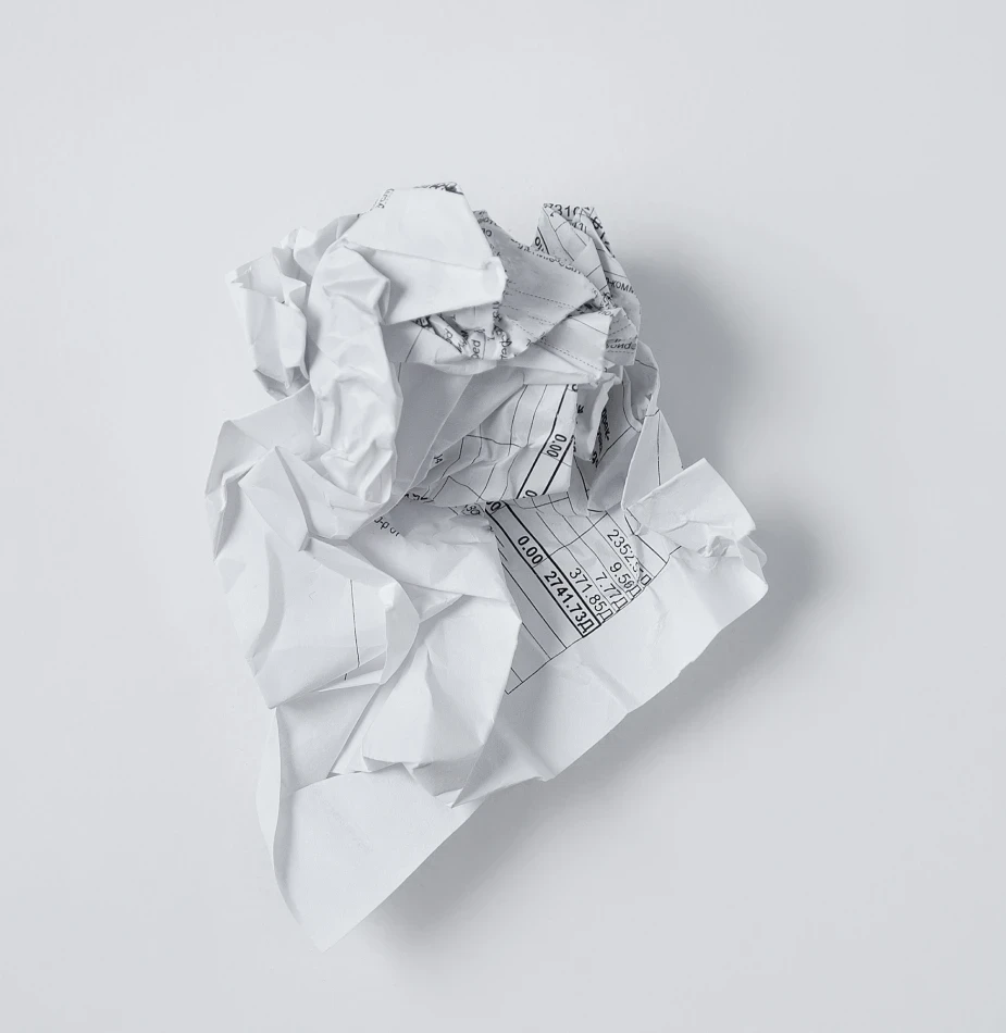 Crumpled financial document with visible spreadsheet data, symbolizing the transformation from paper chaos to digital efficiency.