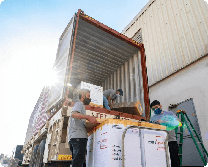 Two office movers efficiently loading boxes into a container, preparing for a corporate move, by Extra Space