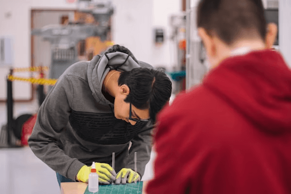 High school student conducting materials science research under PhD mentor guidance in a university laboratory setting