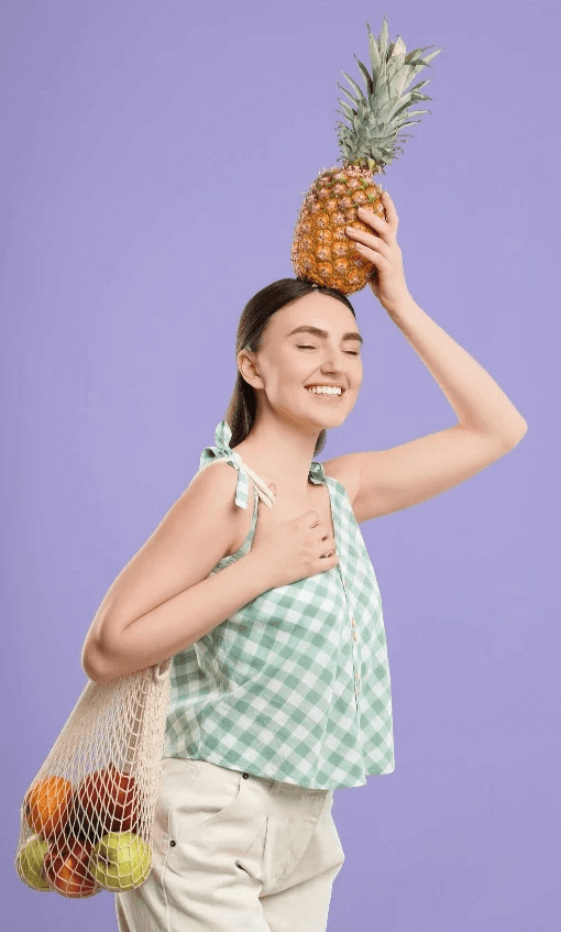 Jeune femme enthousiaste sélectionnant des fruits et légumes frais lors de ses courses pour relever le défi #boosttonmicrobiote.