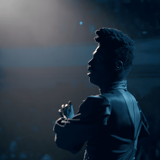 Theatre production with performer on stage under spotlight