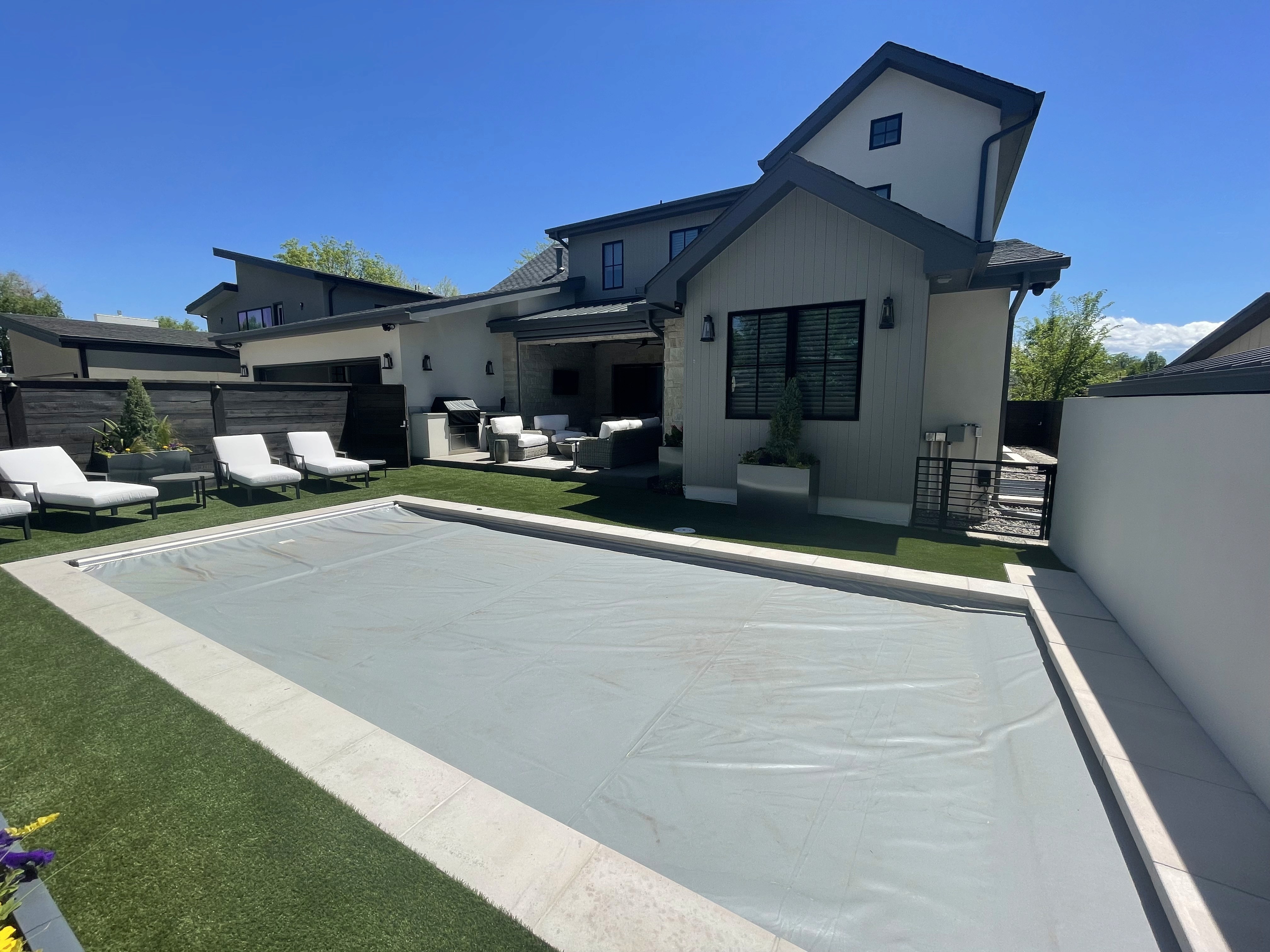 outdoor pool covered with a light grey tarp, located in the backyard of a modern home