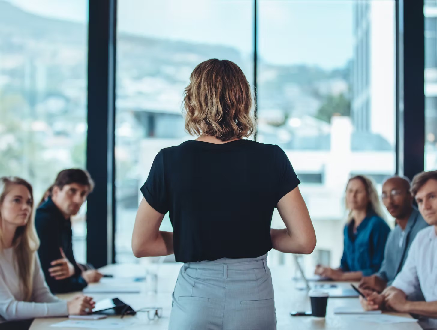 A winding road cuts through rocky terrain, surrounded by patches of green grass and illuminated by sunlight.