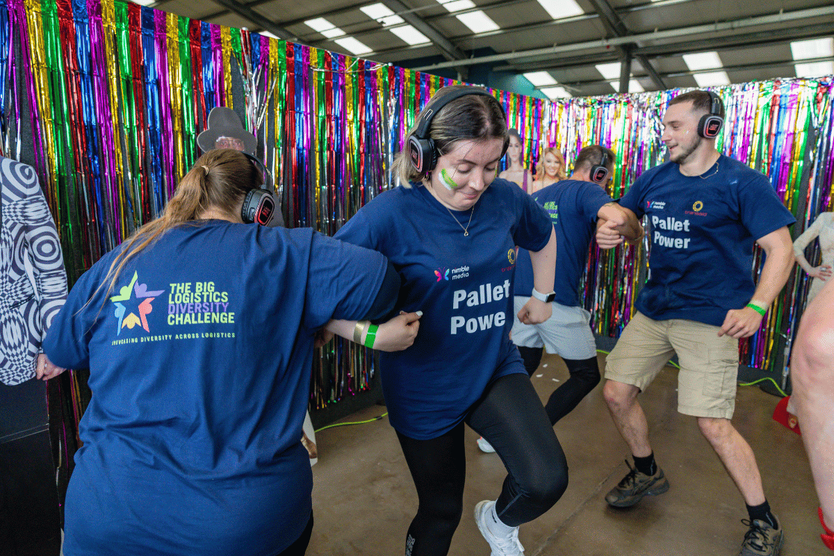 Outdoor team-building event with participants wearing matching blue shirts, taking part in inflatable obstacle courses and games, smiling and cheering, with the words 'ENTER A TEAM' in large bold white and green text across the image.