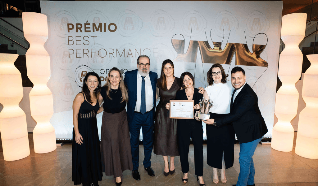 Executivos da Atento posando com troféu ouro e certificado no palco do Prêmio Best Performance 2025