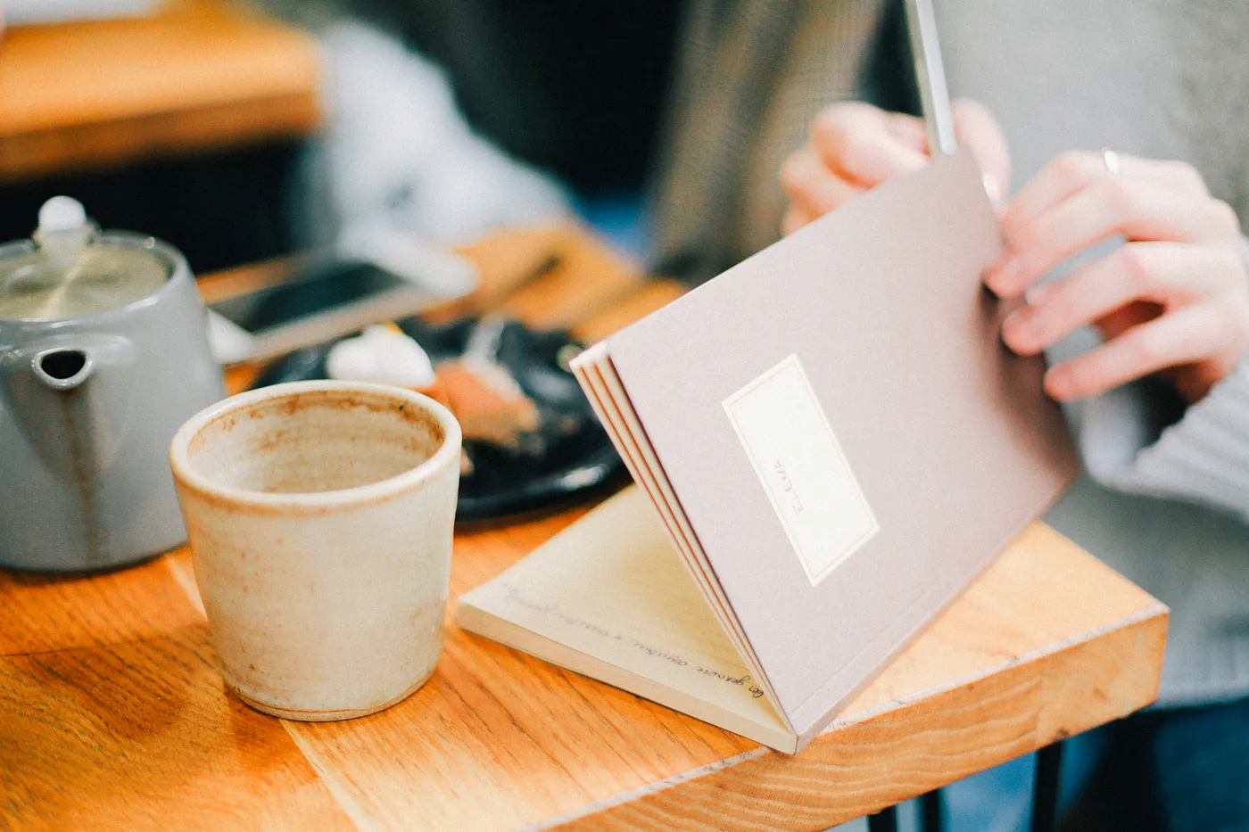 A close up image on a book and a cup at a serene café setting.