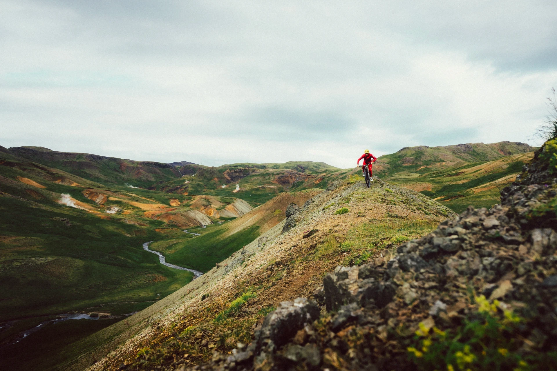 Wide geothermal area with mountainbiker dressed in red