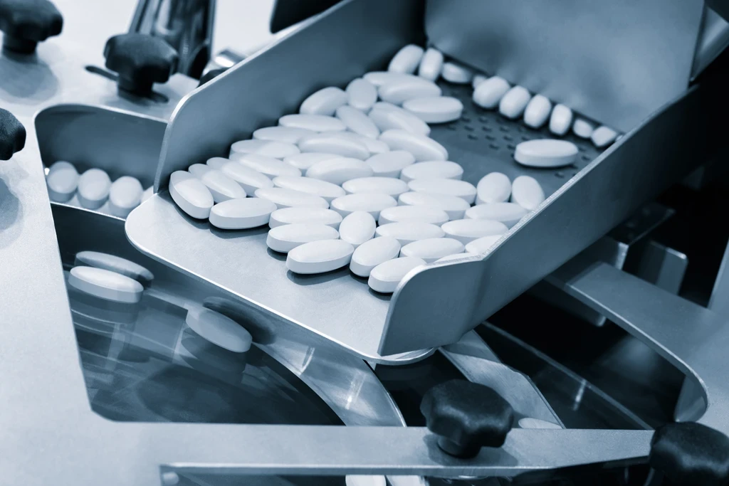 White oval tablets in the tray of a pharmaceutical counting and inspection machine.