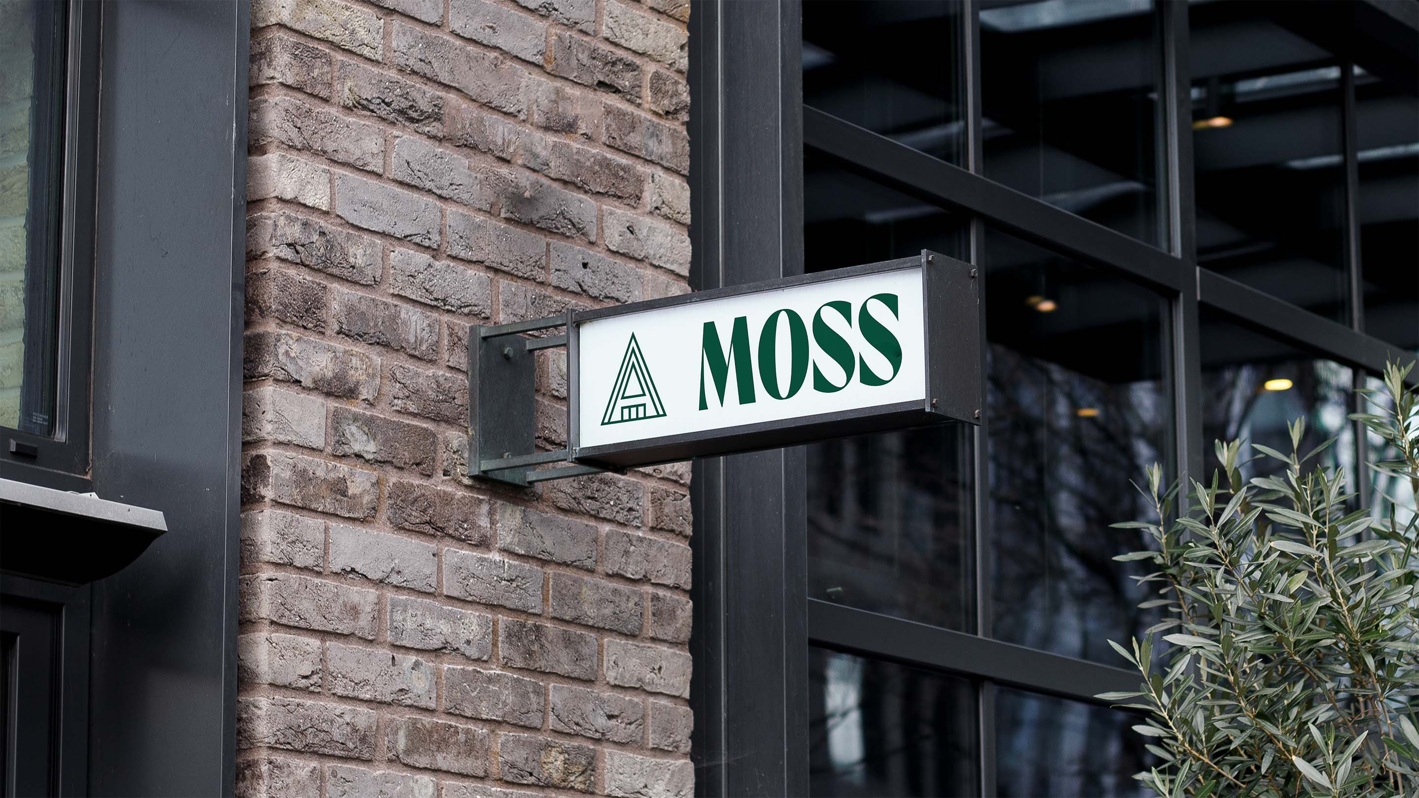 Moss exterior signage mounted on brick wall with cabin icon and green typography