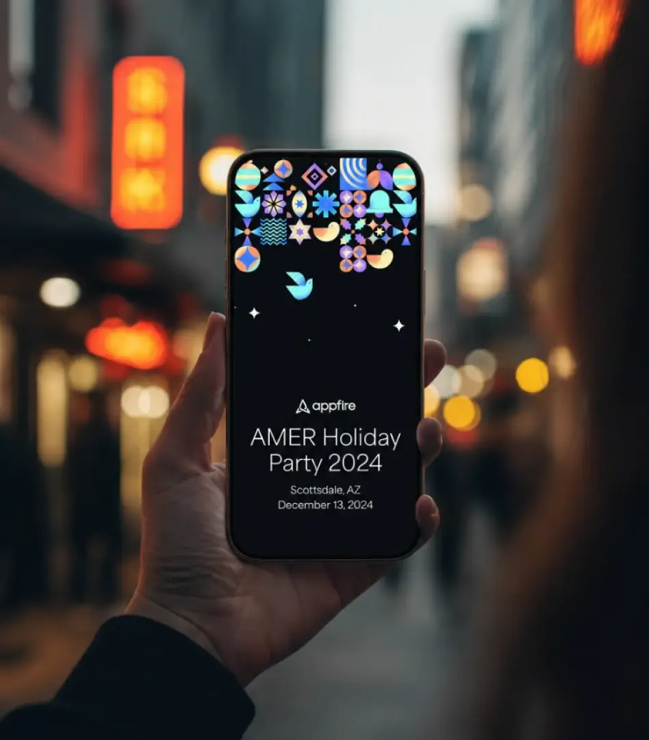 Hand holding a phone displaying the Appfire AMER Holiday Party 2024 event page on a city street at night.