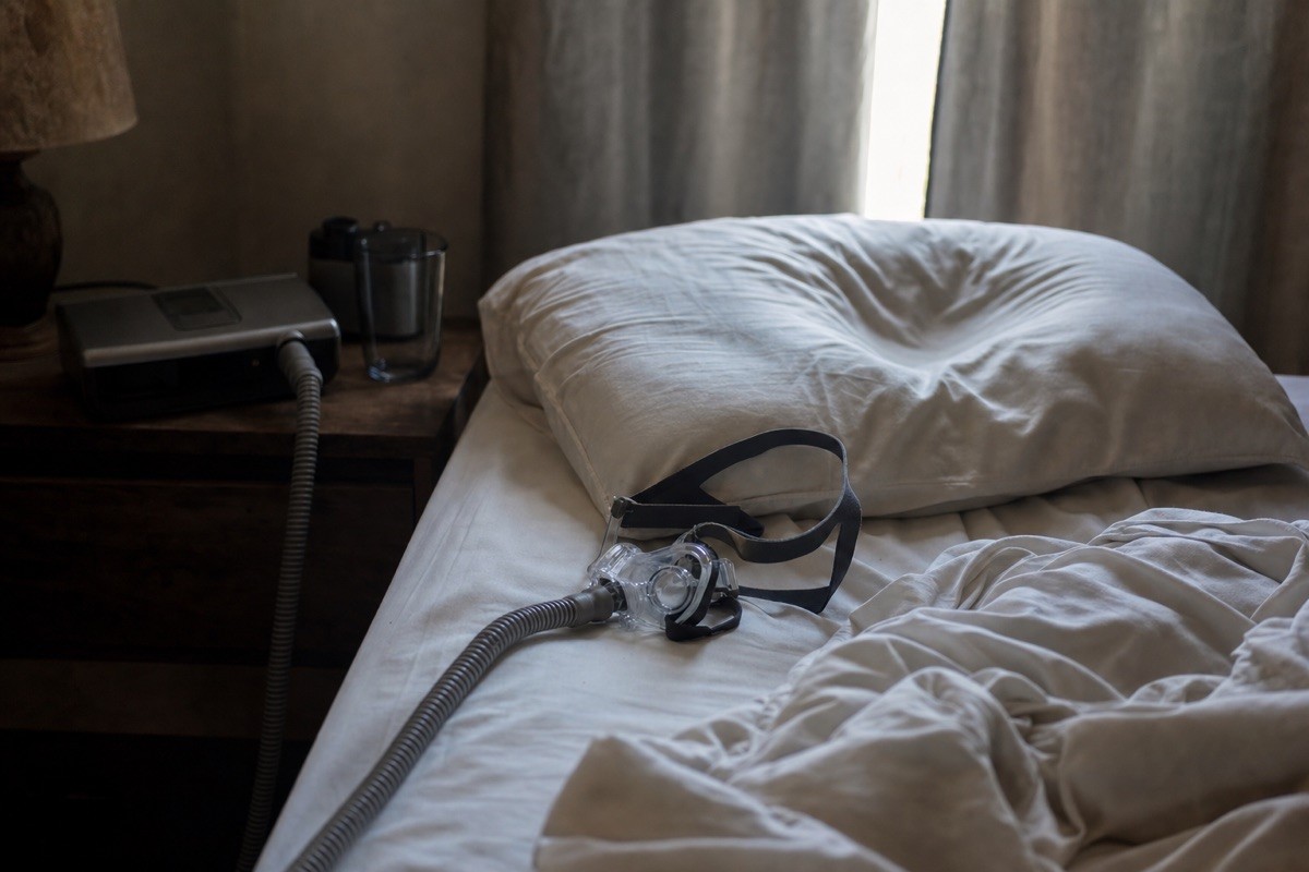 A CPAP mask clawed off onto rumpled sheets at dawn, the little machine humming on the nightstand