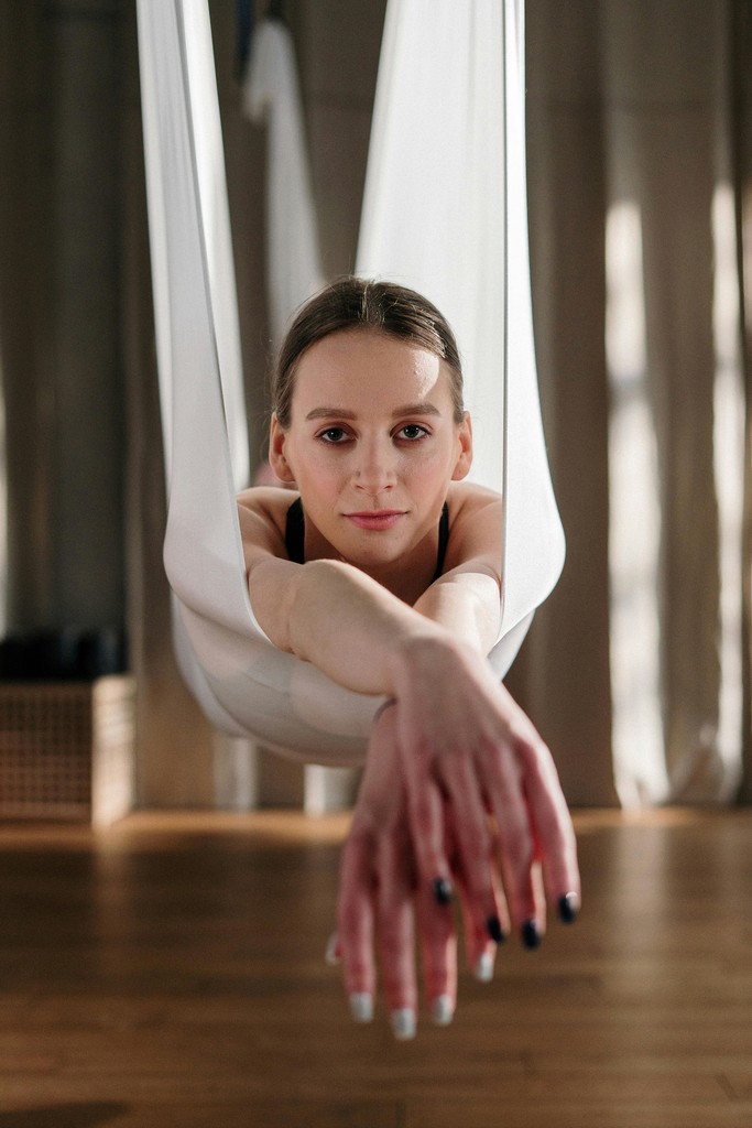 Woman practicing aerial yoga with white hammock