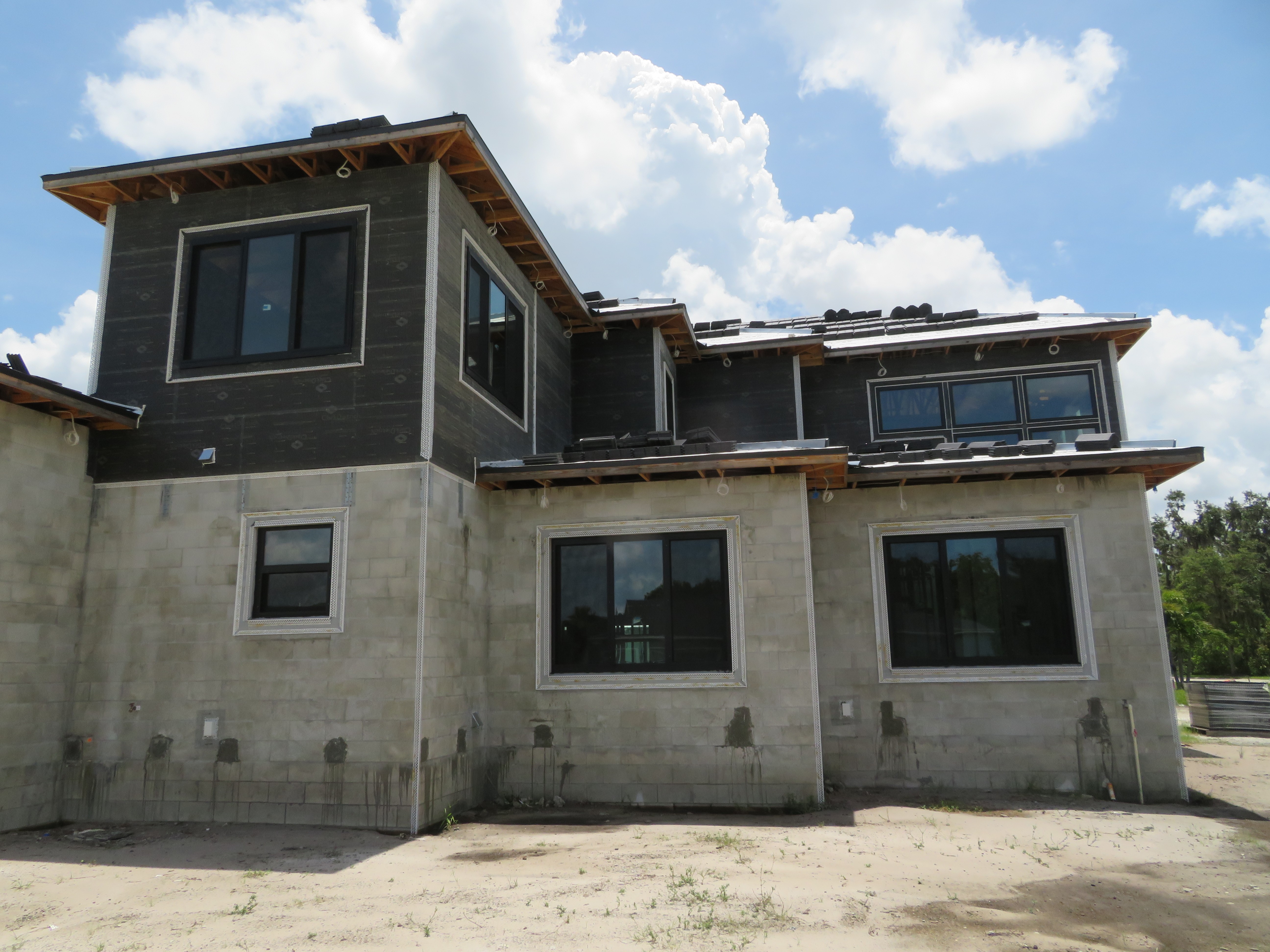 Modern house under construction with concrete base & wood siding.