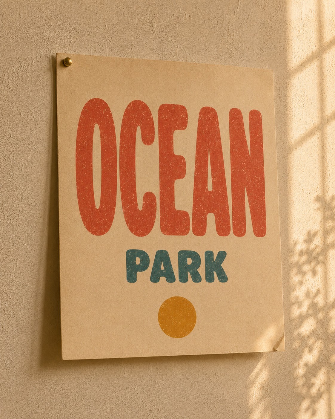 Poster on a textured wall reading "OCEAN PARK" in bold red and blue letters above an orange dot, with soft sunlight casting shadows.