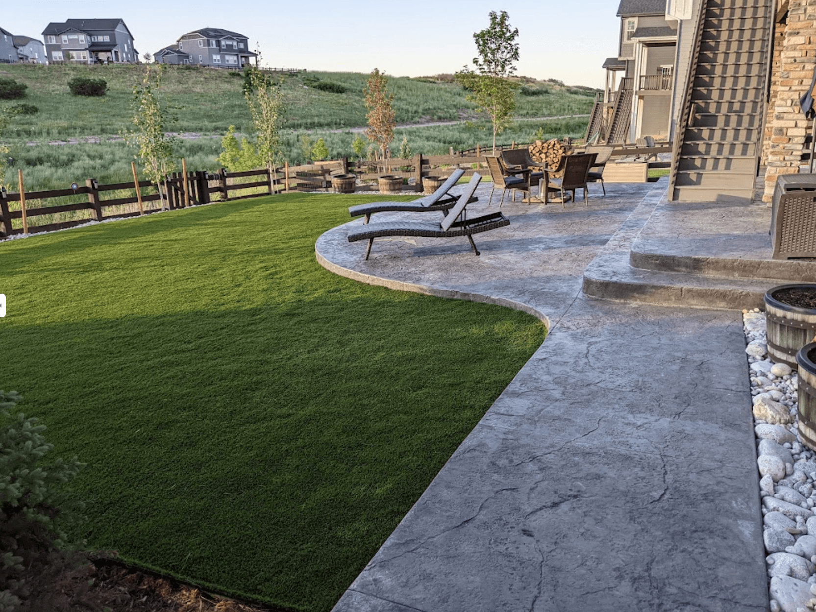 artificial grass installation in the backyard, with a large patio area featuring elegant concrete decorative stone walls