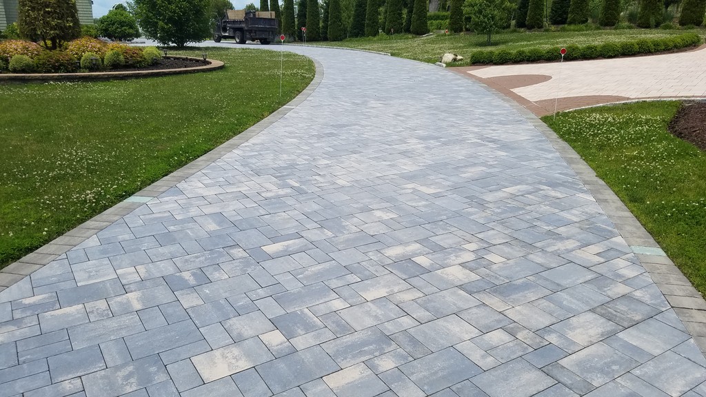 Curved light-gray paver walkway along green lawn