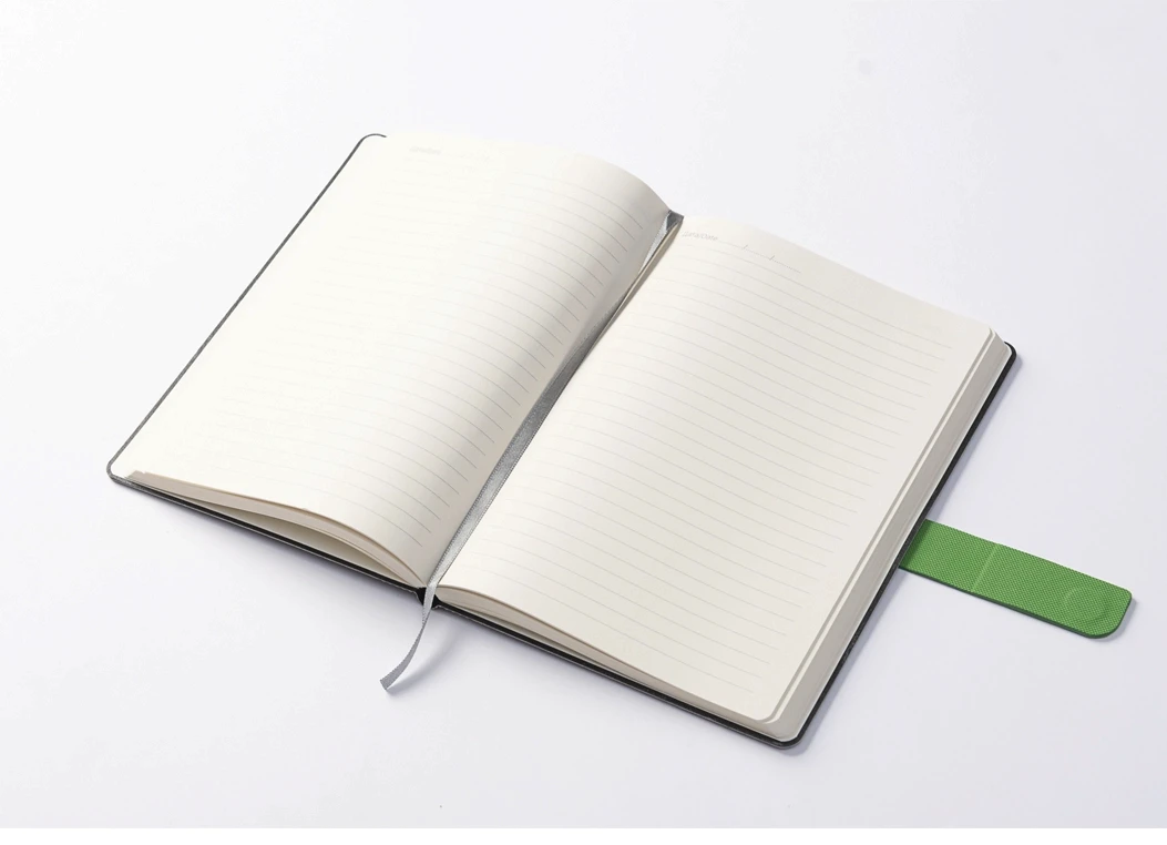 Open journal with ruled ivory pages and green strap visible on the side