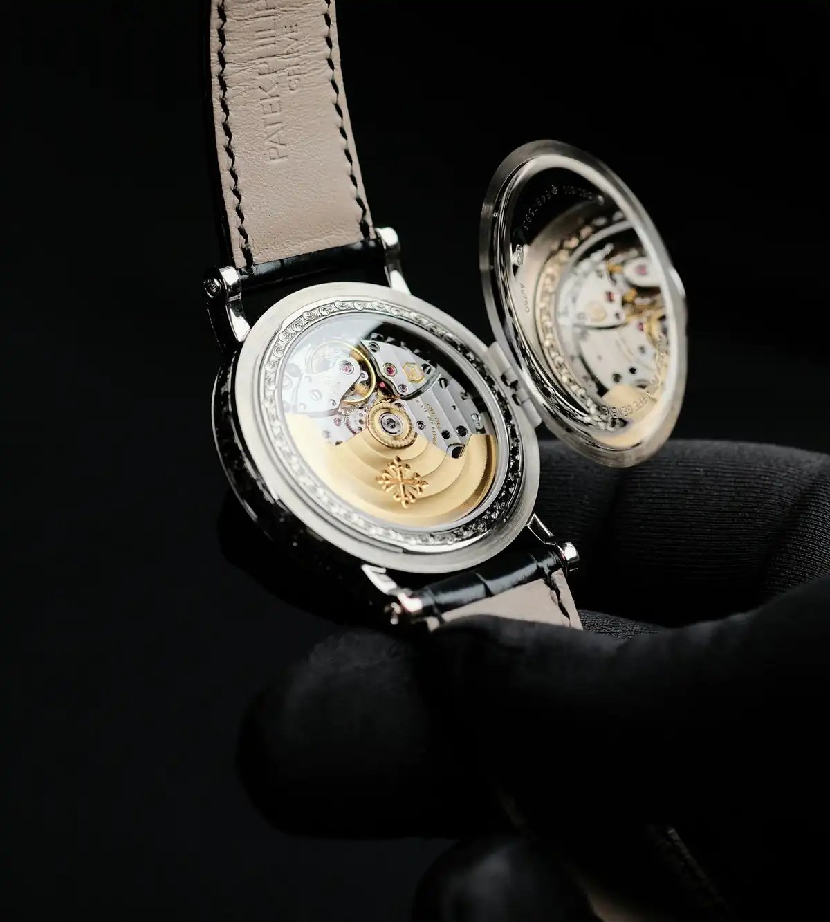 Patek Philippe dress watch on a leather strap with its hinged case back open to show the movement