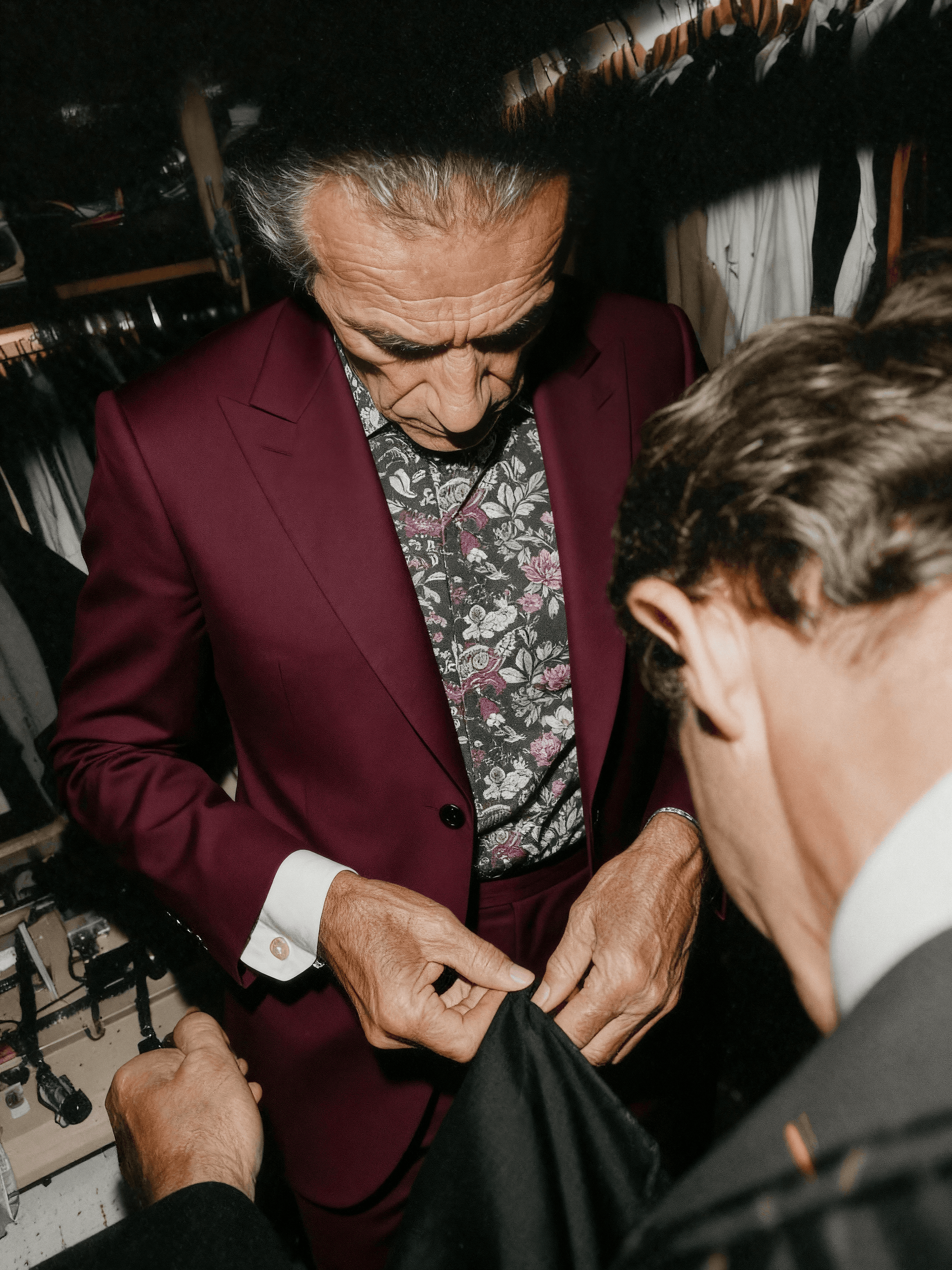 AI-generated campaign visual of a tailor fitting a burgundy floral shirt and suit on a client, created by Myrovia Labs for Forzieri. AI creative direction for classic menswear craftsmanship and luxury tailoring.