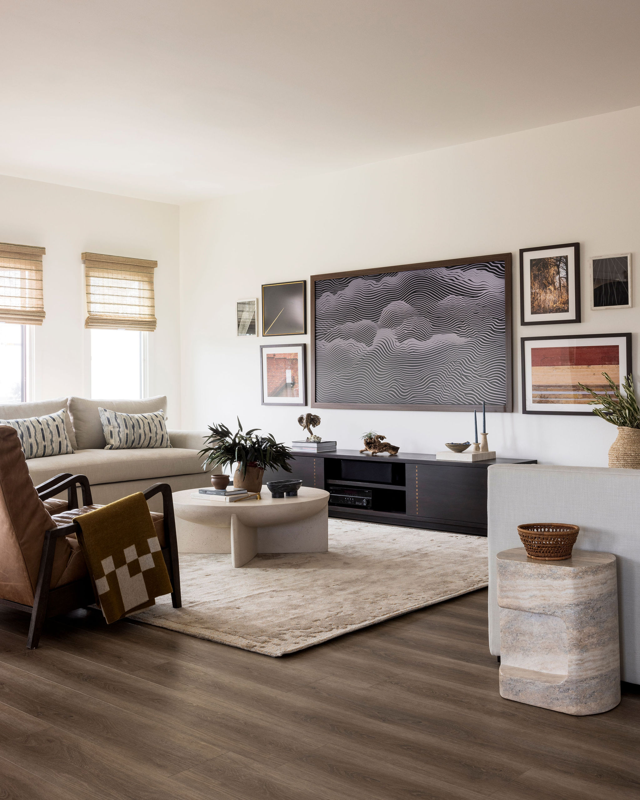 Spacious coastal living room featuring soft neutral tones, natural textures, and a statement art gallery that blends in with the mounted TV vertical shot.