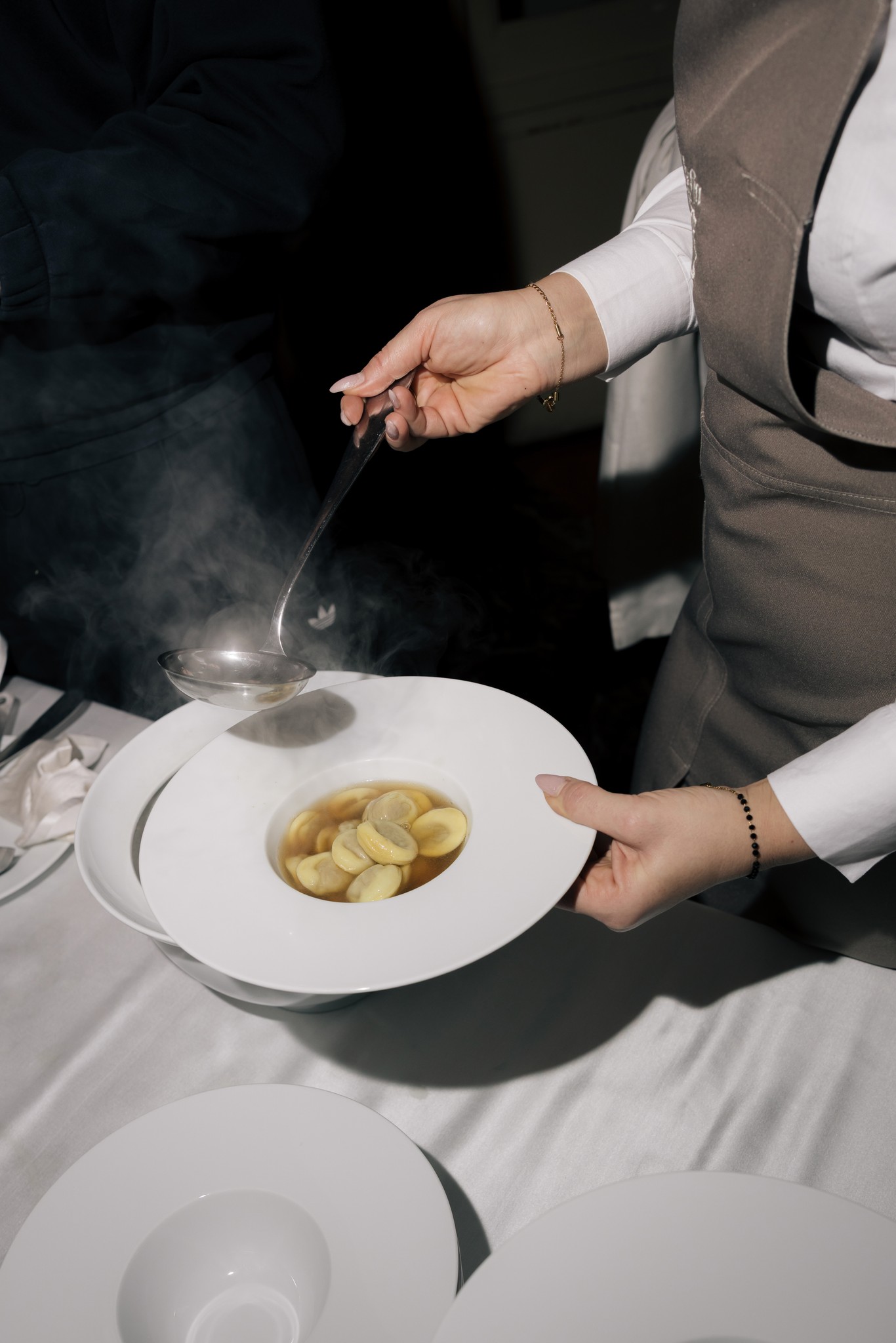 Mano dello sposo versa salsa su piatto di pasta fresca durante il ricevimento di matrimonio al Circolo di Lettura di Parma