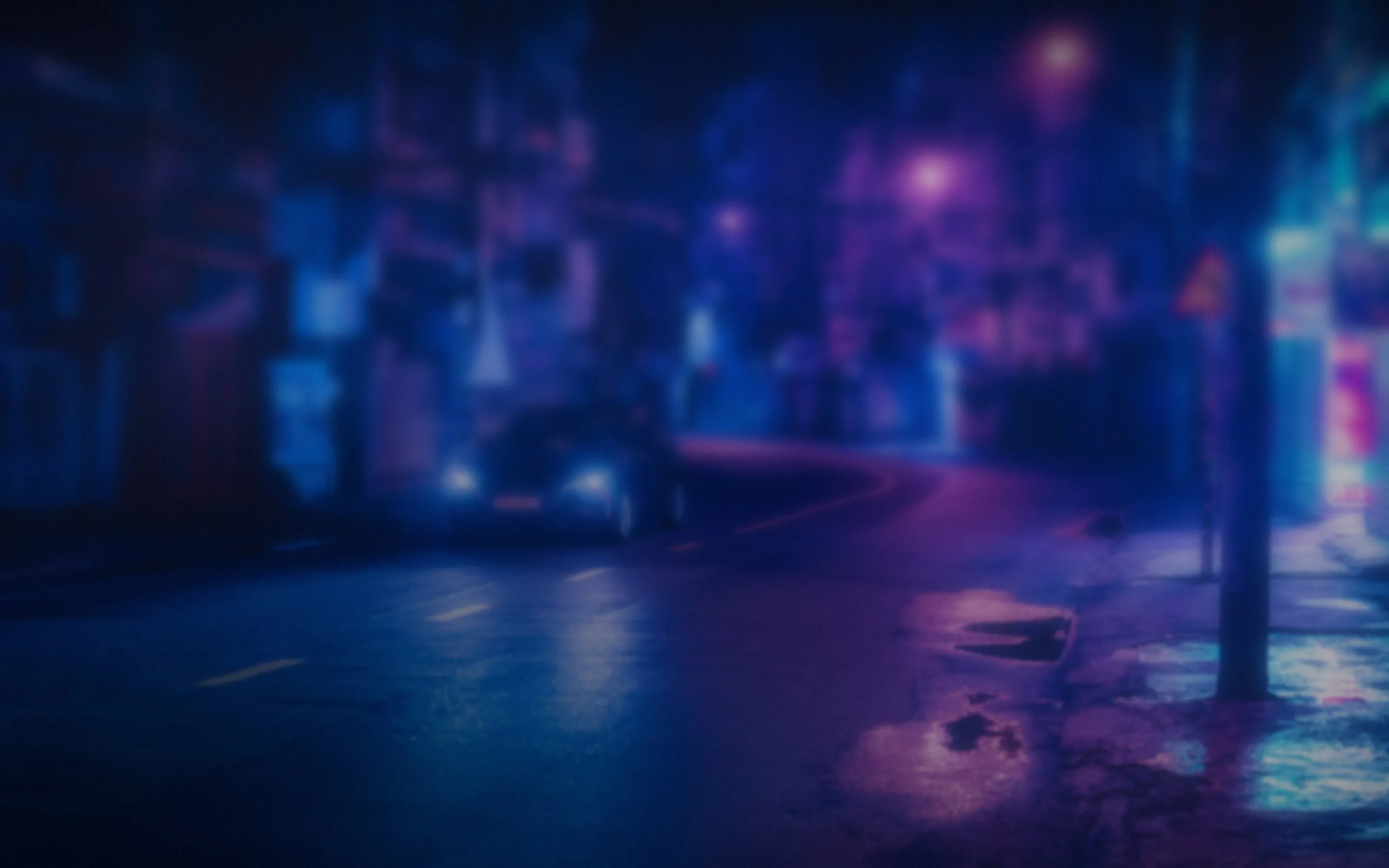 A wet street at night lit in blue and violet neon