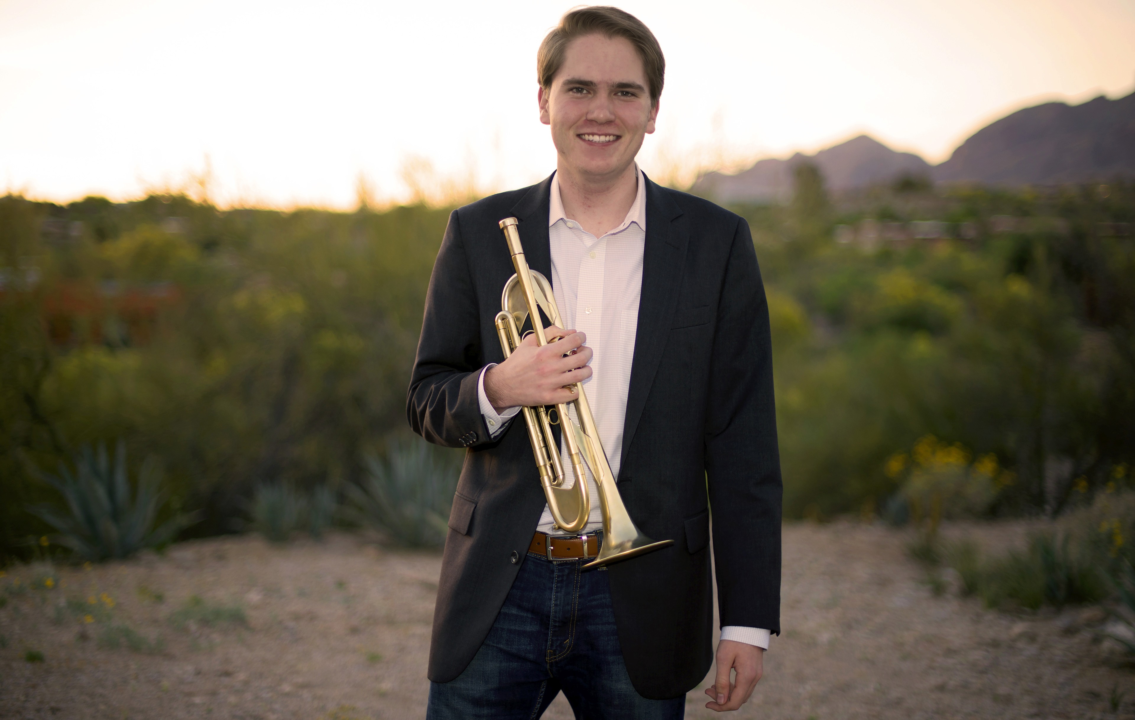 Alex holding his trumpet against a desert backdrop
