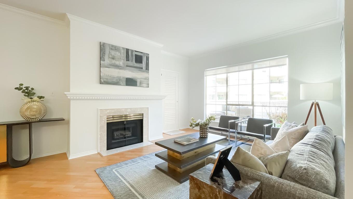 A bright living room featuring a cozy seating area, a modern fireplace, and large windows letting in natural light.