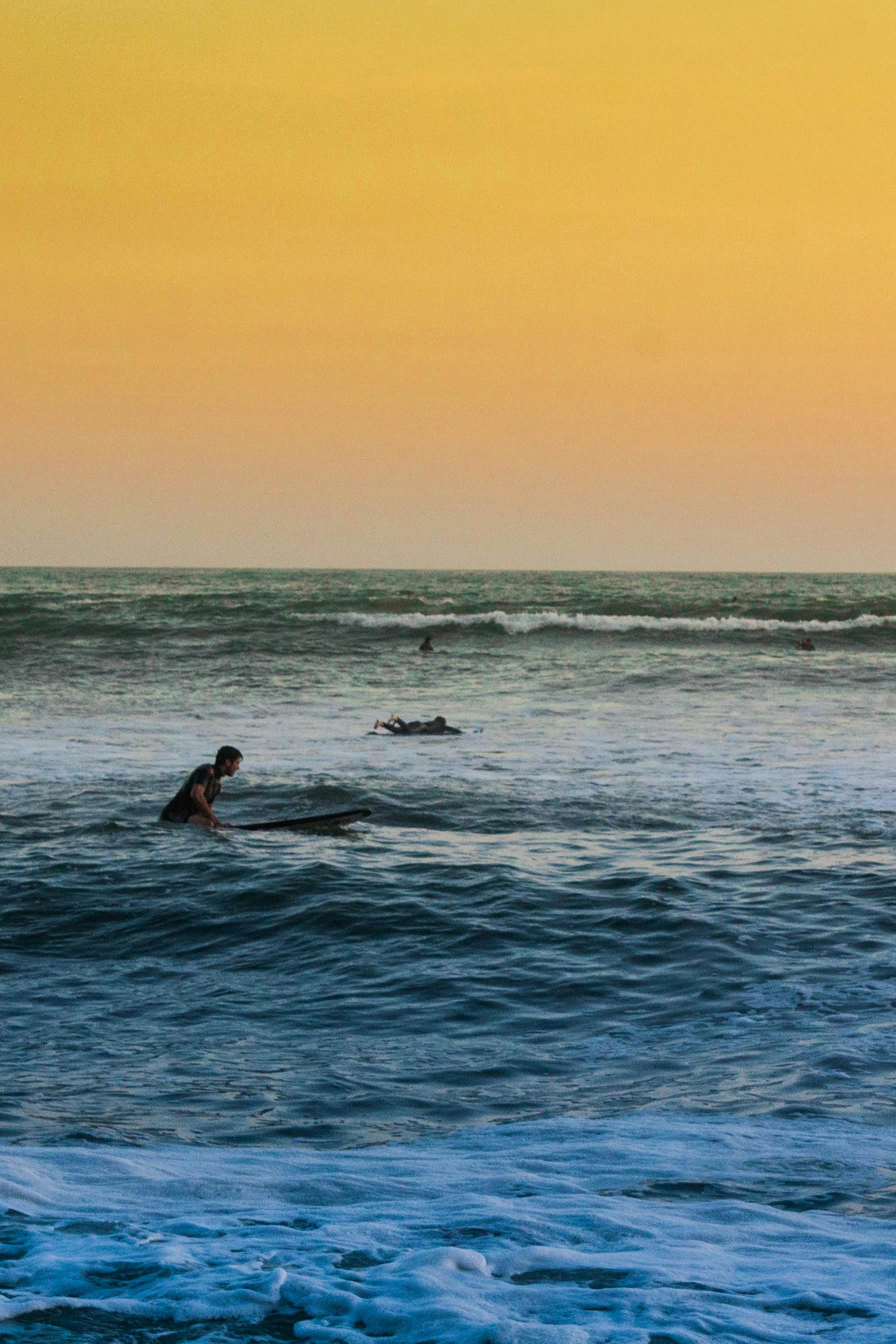 Surfers in the ocean at sunset – surfboard rental in makaha.