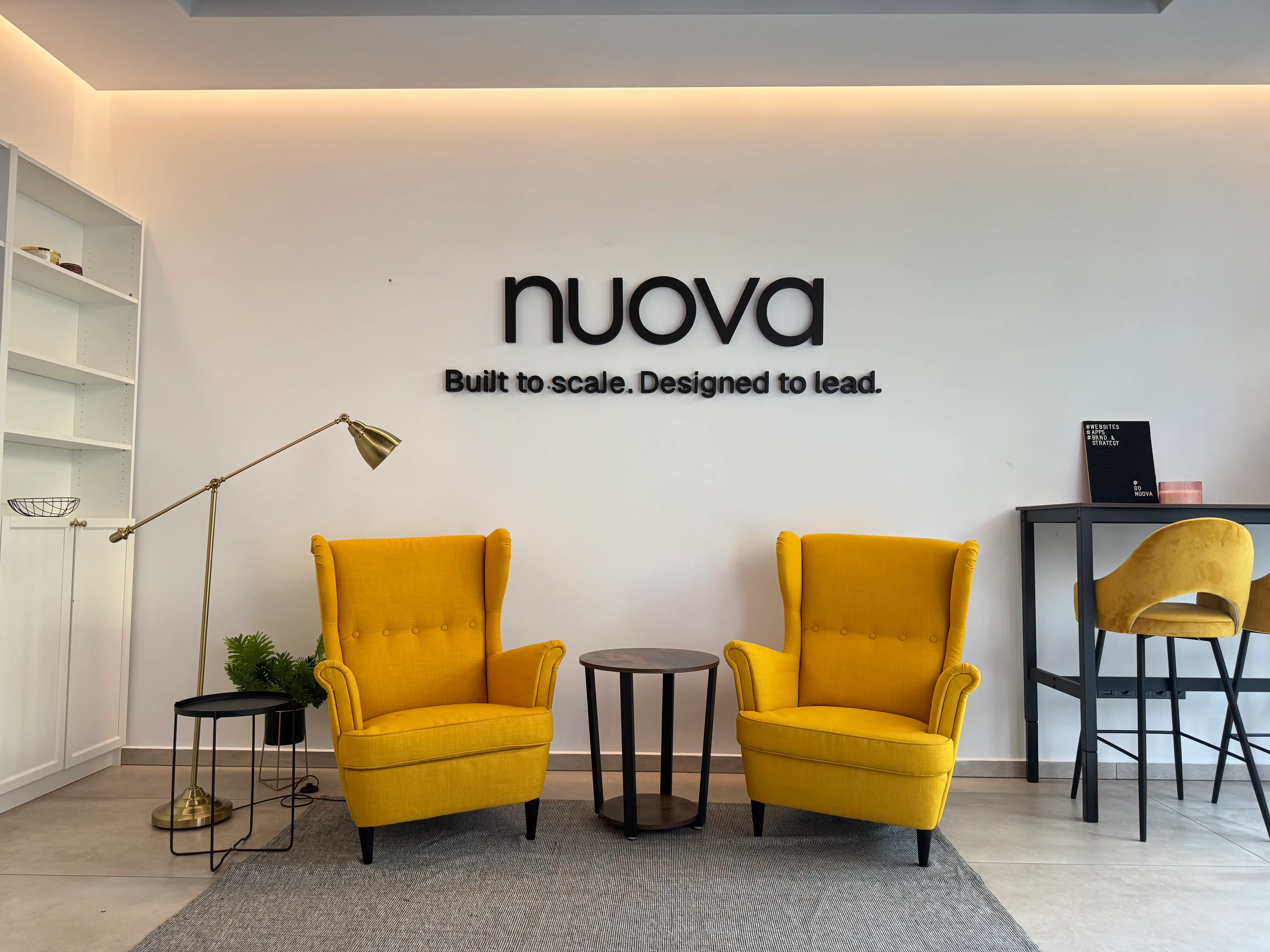 A modern office with colourful furniture and a big Nuova logo on the wall