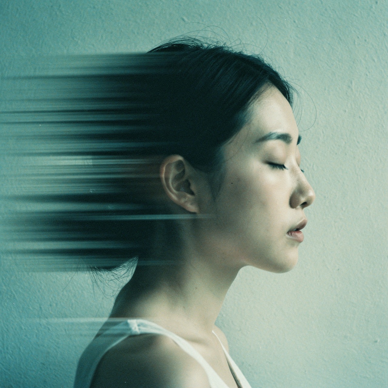 A serene woman with closed eyes leans against a textured wall. Her hair blurs into motion lines, creating a sense of speed and calm introspection.