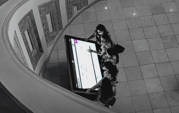 A top down photo of a group of people using an interactive wayfinding kiosk