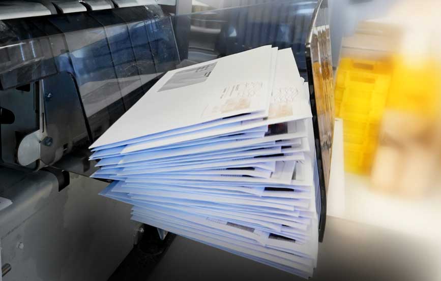 Envelopes freshly printed sitting inside a tray.