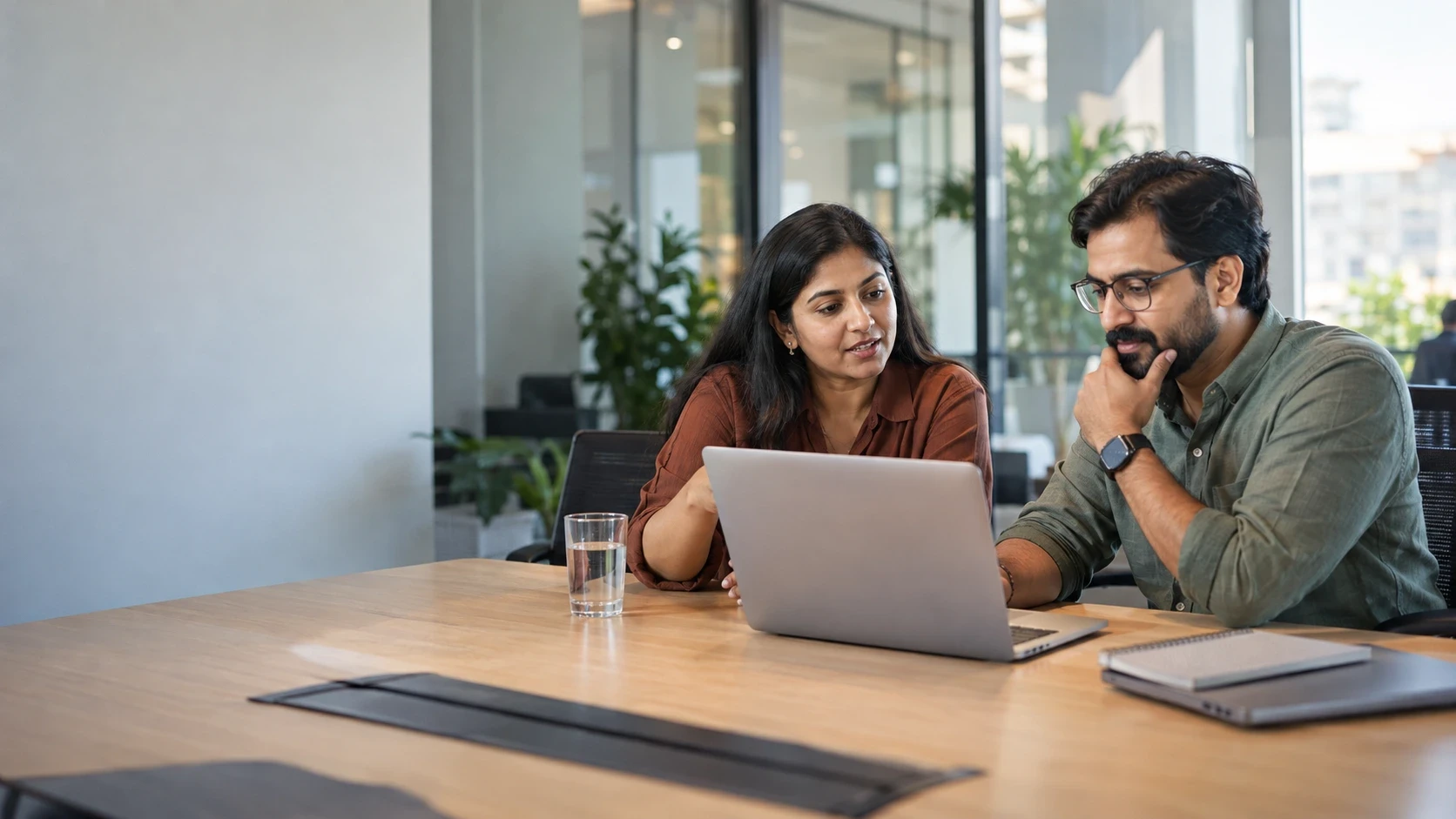 Technical hiring team reviewing candidate evaluation software on a laptop in a modern office.