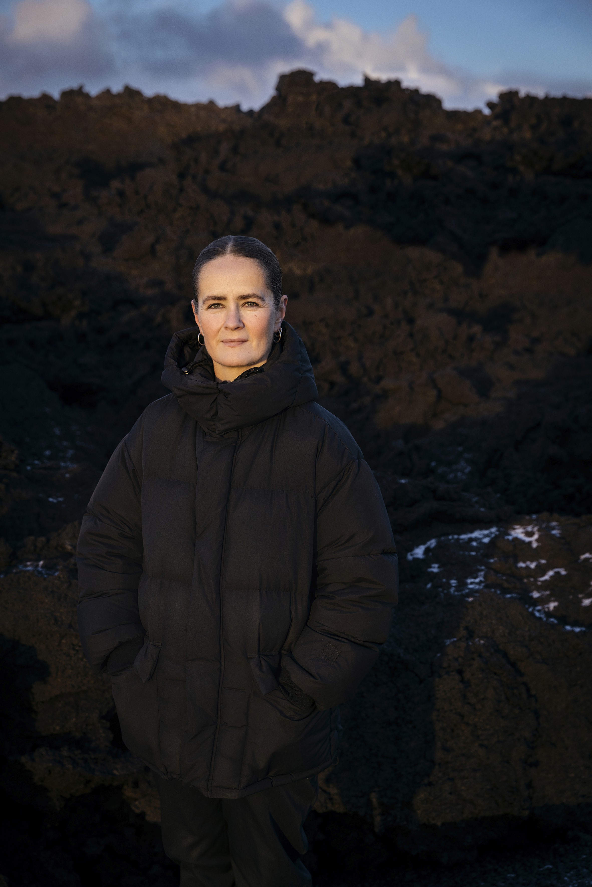 Icelandic architect Arnhildur Pálmadóttir, founder of s.ap architects, stands in front of a rugged lava field, reflecting her team’s focus on volcanic landscapes and sustainable architecture.