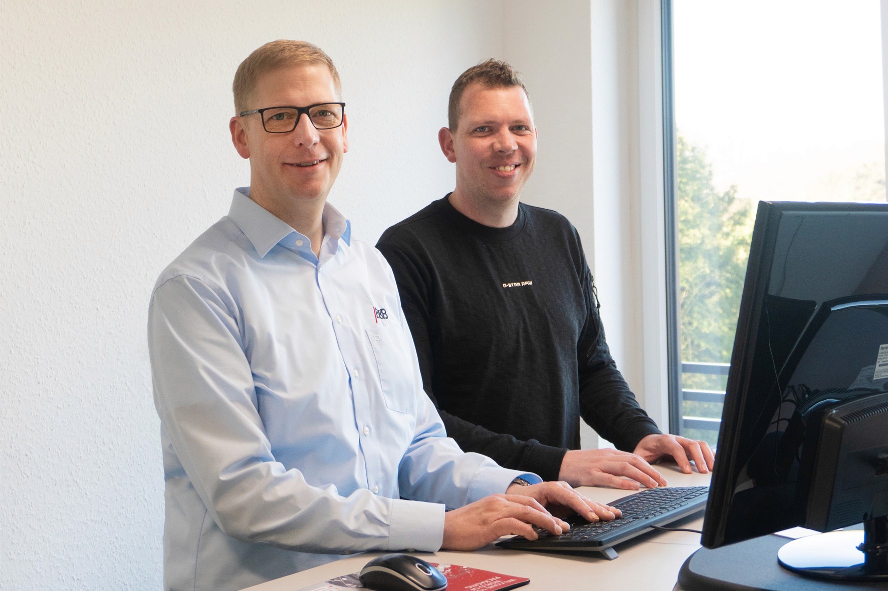 Two smiling men in the office. Professionals working at the computer, office workers.